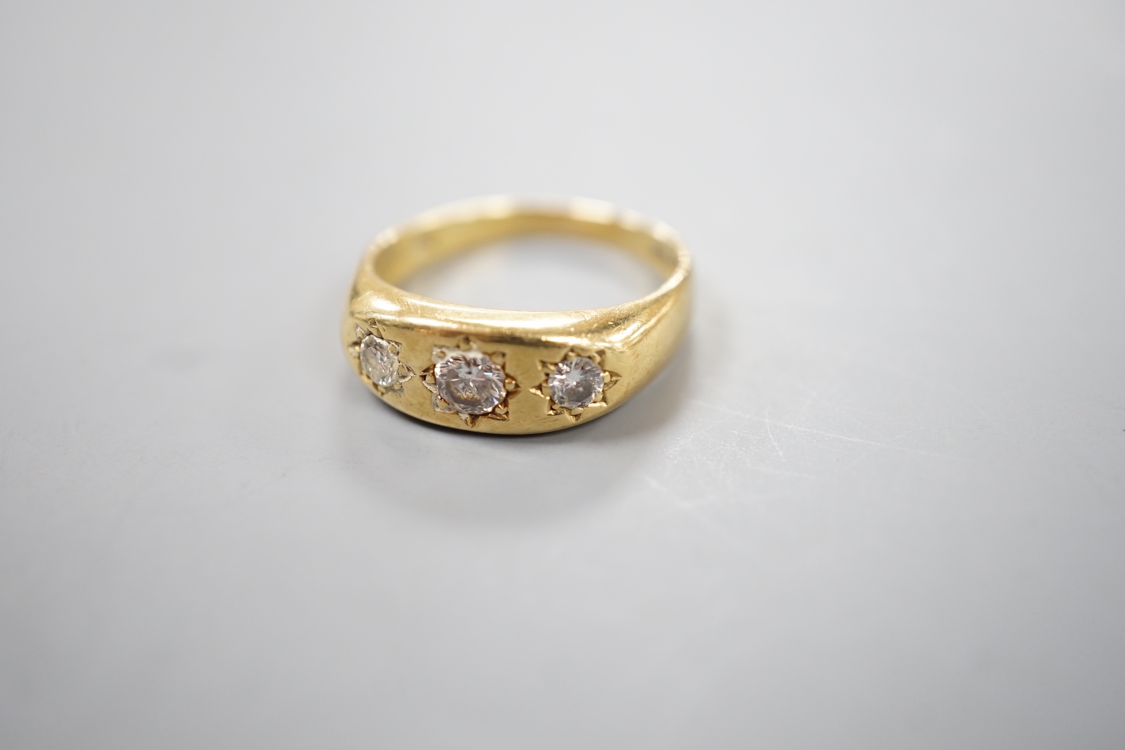 An 18ct gold and three stone gypsy set diamond ring, size S, gross weight 7.1 grams.